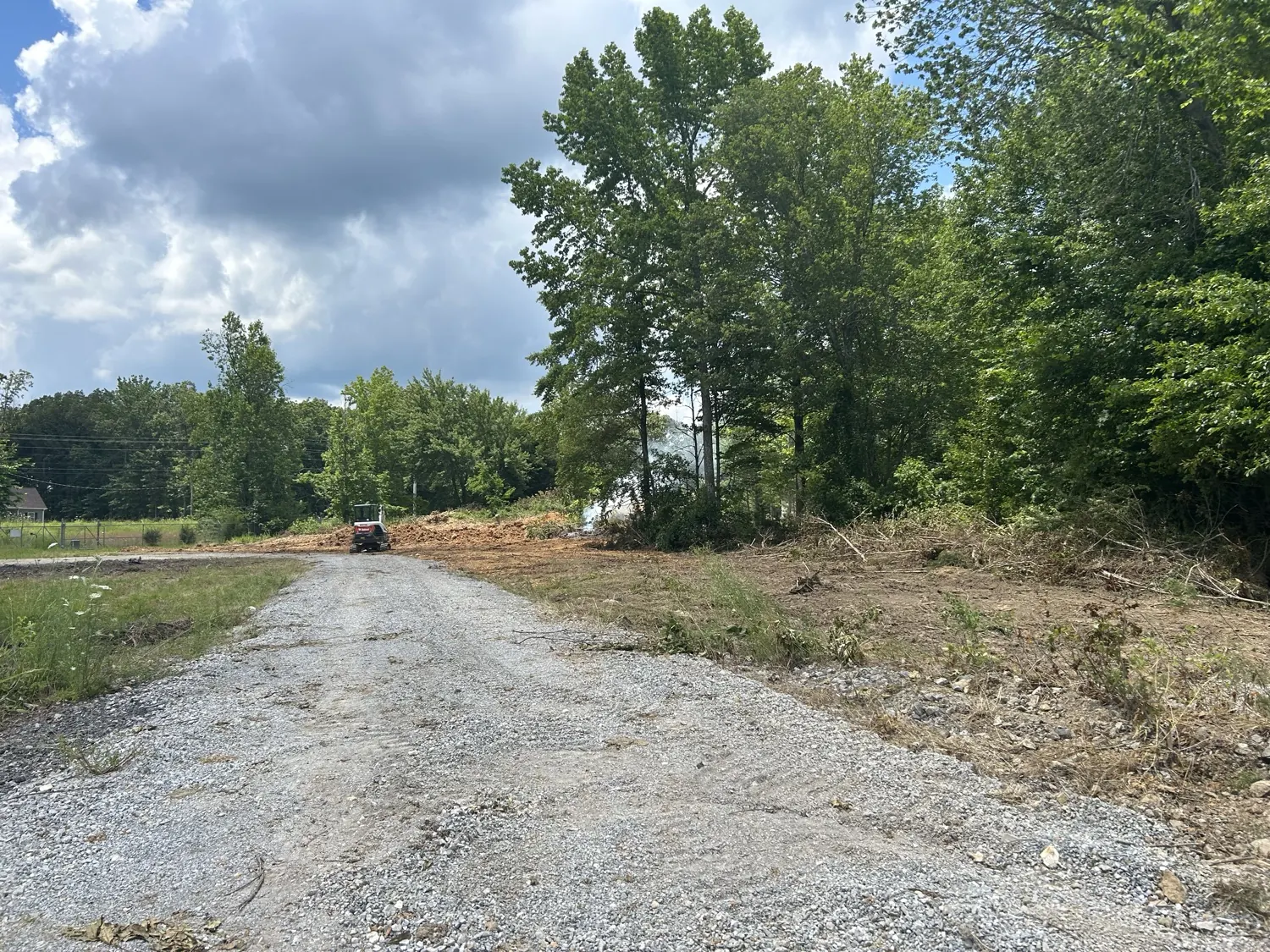 A gravel driveway leading into a cleared lot