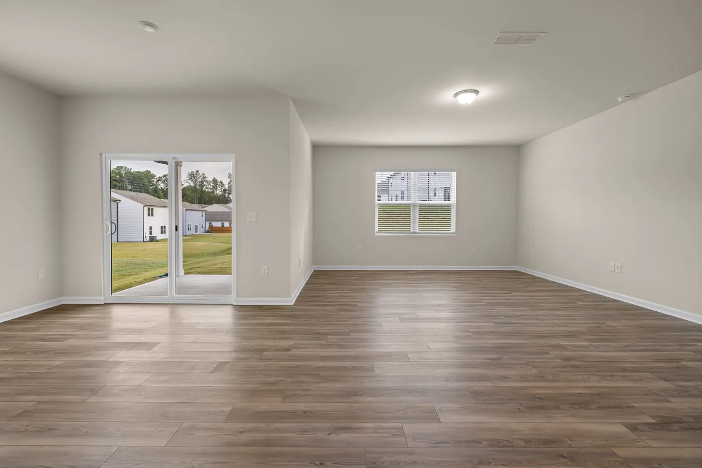 A bright, empty living room with wood-look floors, ready for new occupants